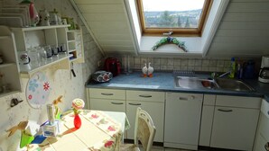 A kitchen with a skylight, a sink, and a dining area with a table and chairs. - Apartment house Monika (Bergenhausen)