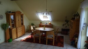 A dining area with a round table, wooden chairs, a cabinet, and a radiator. - Apartment house Monika (Bergenhausen)