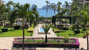 Um resort com piscina, palmeiras e vista para o mar.