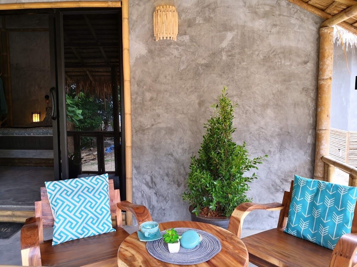 Un espacio de estar al aire libre con madera, que incluye dos sillas, una mesa, una planta en maceta y una pared con textura.