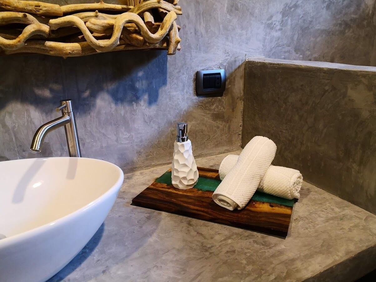 A bathroom with a white sink, a wooden tray with towels, and a textured soap dispenser.