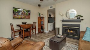Una sala de estar con chimenea, un comedor y una cocina al fondo.