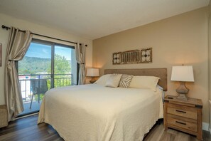 Una camera d'albergo con un letto grande, due comodini con lampade, vista sull'esterno e un elemento decorativo a parete.