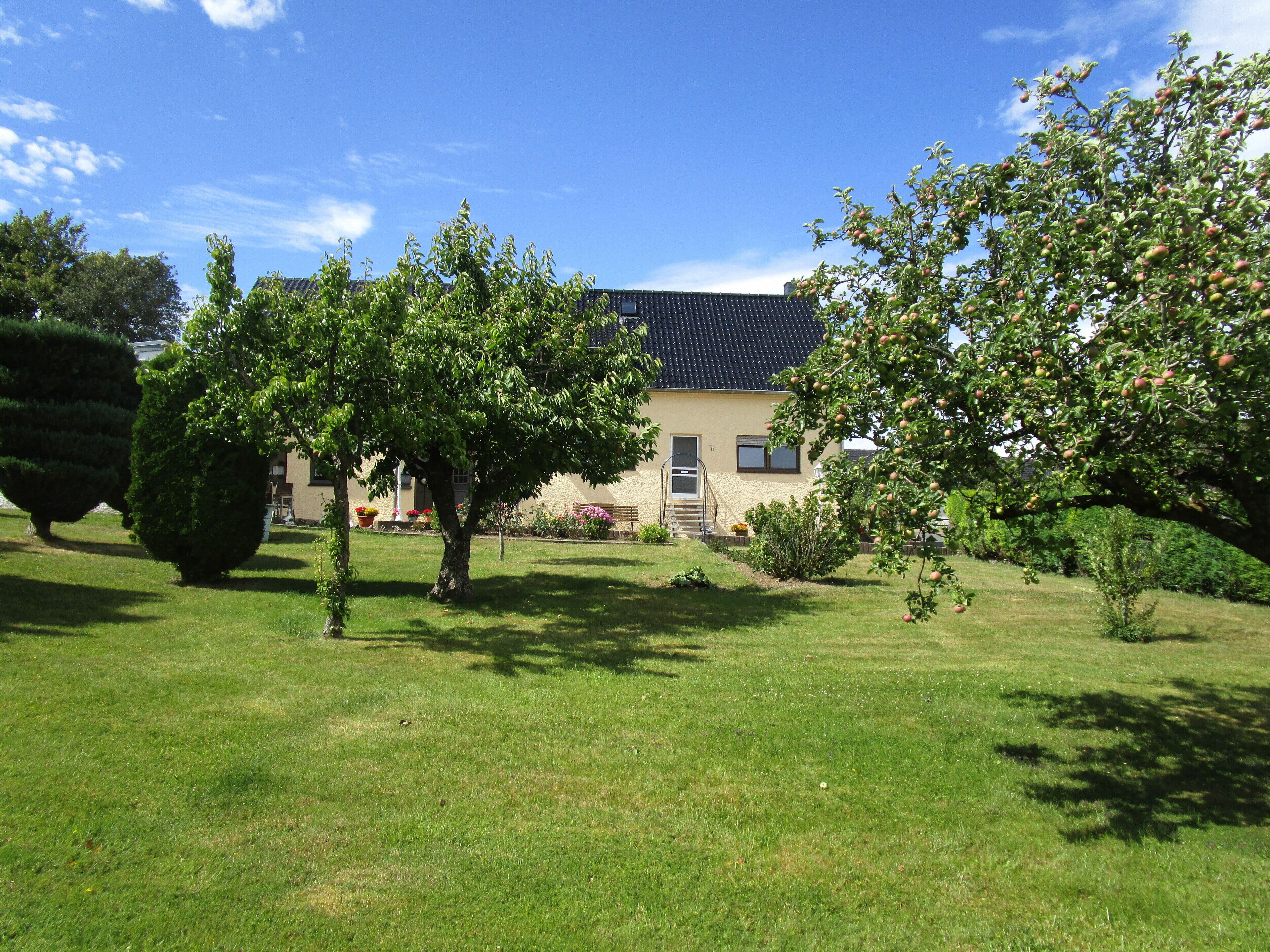 A house with a tiled roof, surrounded by a well-maintained lawn and trees.