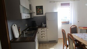 A compact kitchen with a sink, cabinets, a refrigerator, and a dining area with chairs and a table. - Holiday home Nice view for 1 - 5 persons (Esch)