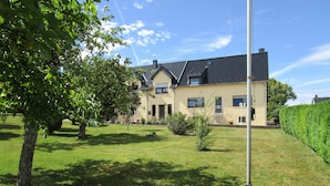 A two-story house with a sloped roof, a well-maintained lawn, and a hedge along the side. - Holiday home Nice view for 1 - 5 persons (Esch)