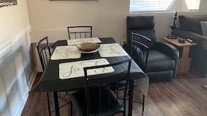 A dining area with a black table, four chairs, and a framed picture of a park entrance.