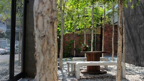 A courtyard with a table and benches, surrounded by trees and a brick wall. - Owl Homestay (Kuala Lumpur)