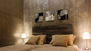 A bedroom with a large bed, two bedside lamps, and three wall-mounted paintings. - Owl Homestay (Kuala Lumpur)