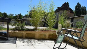 Un patio con un edificio tradicional, un árbol y una silla.