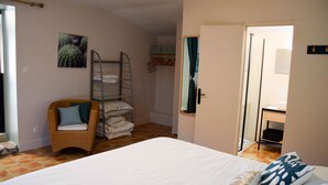 Un dormitorio con una cama, una silla, una cama litera, un armario y una puerta que da a otra habitación.