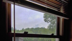 Une fenêtre donnant sur un espace verdoyant et une terrasse en bois.