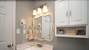 Une salle de bain avec un lavabo en marbre, un grand miroir, un sèche-cheveux et un porte-serviettes.