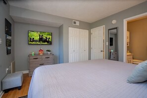 Un dormitorio con cama, cómoda, televisor y puerta.