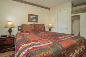A bedroom with a large bed, two bedside lamps, a nightstand with a lamp, a dresser, and a door. - OGP503 downtown near Ripley's Aquarium & Anakeesta (Gatlinburg)
