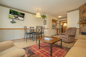 A living room with a dining area, a kitchen in the background, and a large window with a view of a park. - OGP503 downtown near Ripley's Aquarium & Anakeesta (Gatlinburg)