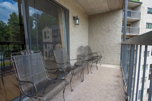 A balcony with metal chairs and a table, a glass door, and a textured wall. - OGP503 downtown near Ripley's Aquarium & Anakeesta (Gatlinburg)