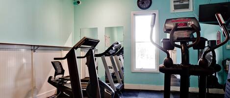 A gym with treadmills, a stationary bike, and a rowing machine.