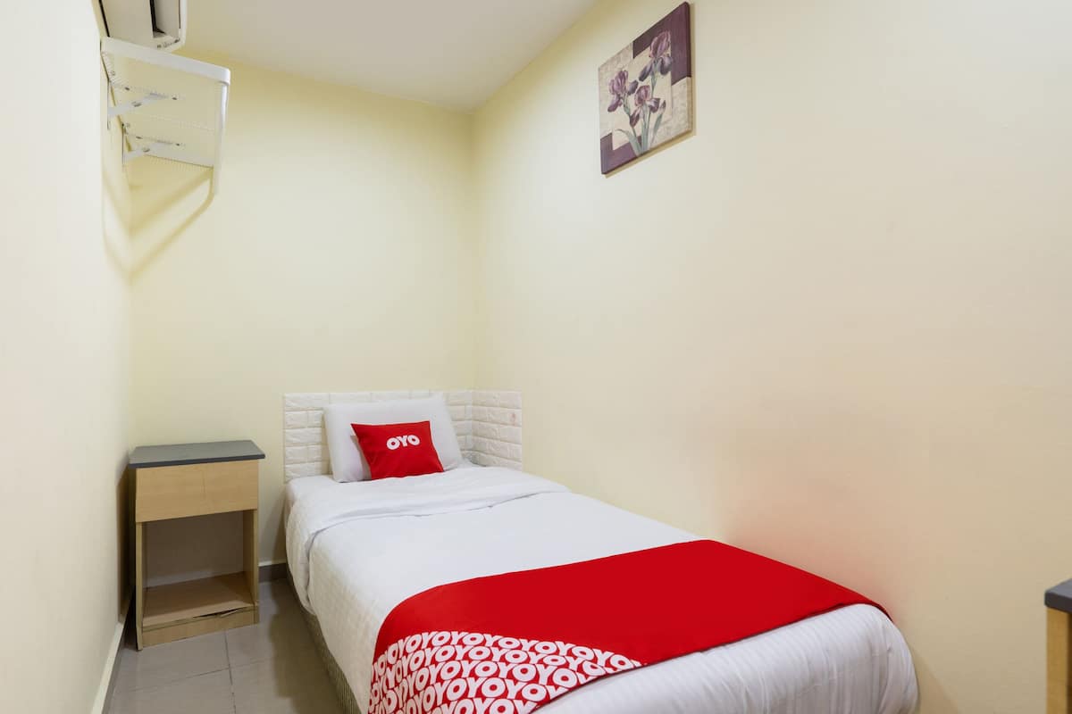 A small, neatly arranged bedroom with a bed, a nightstand, and a wall-mounted air conditioning unit.