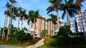 A multi-story hotel with a central courtyard surrounded by palm trees and lush greenery. - Solea Palm Resort Mactan (Cordova)