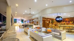A modern hotel lobby with wicker furniture, a bar area, and a visible restaurant named 'earth'. - Solea Palm Resort Mactan (Cordova)