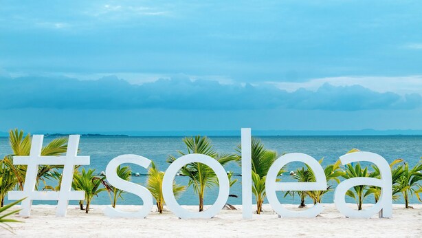 A beach with large white letters spelling "solea" and palm trees in the foreground. - Solea Palm Resort Mactan (Cordova)