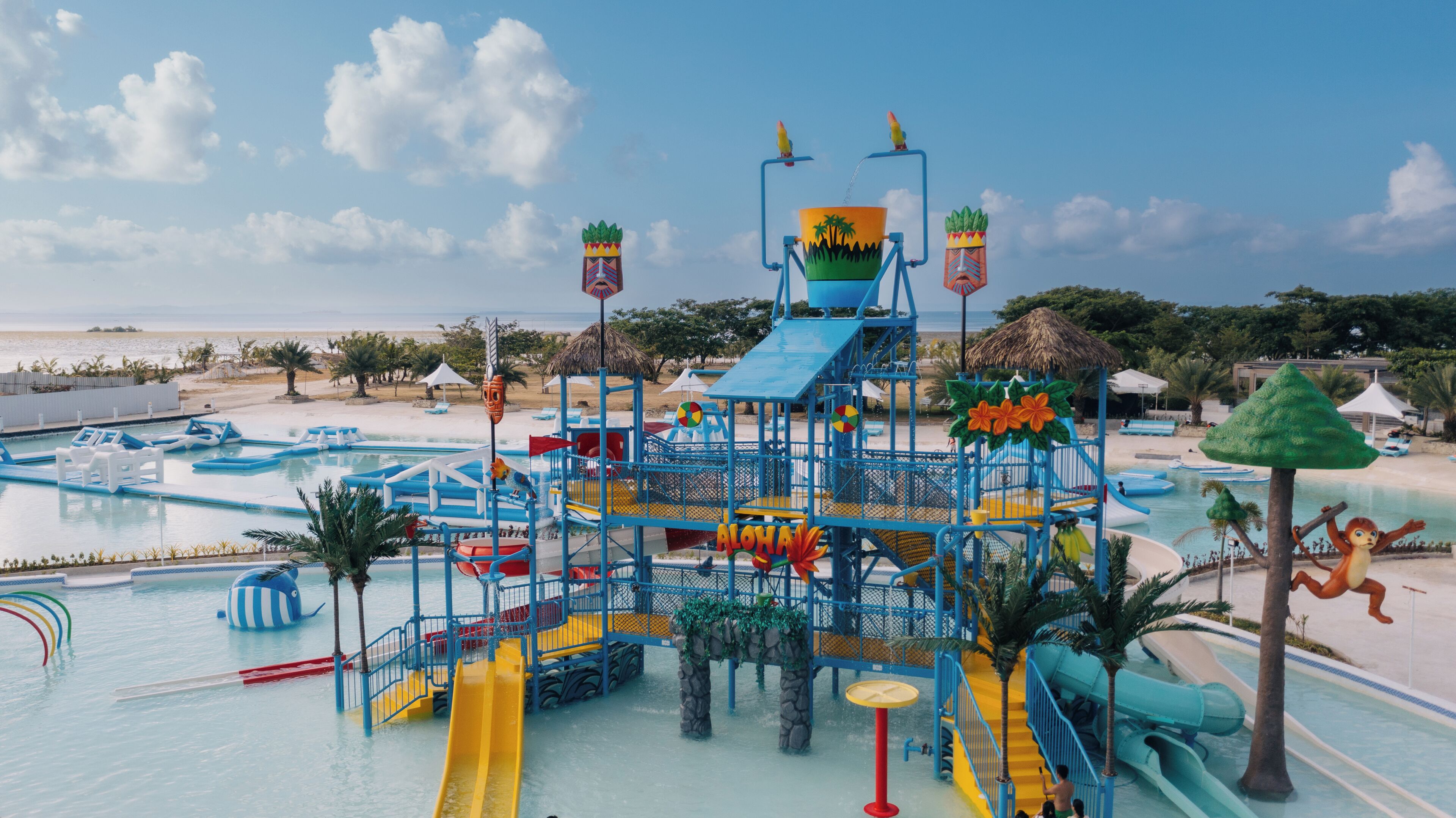 A water park with multiple slides and play structures, surrounded by pools and a beach.