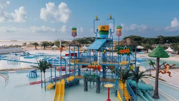 A water park with multiple slides and play structures, surrounded by pools and a beach.
