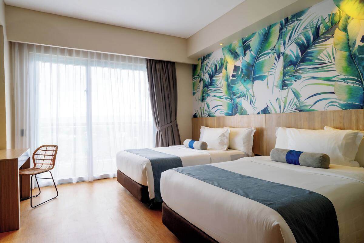 A hotel room with two beds, a desk, and a chair.