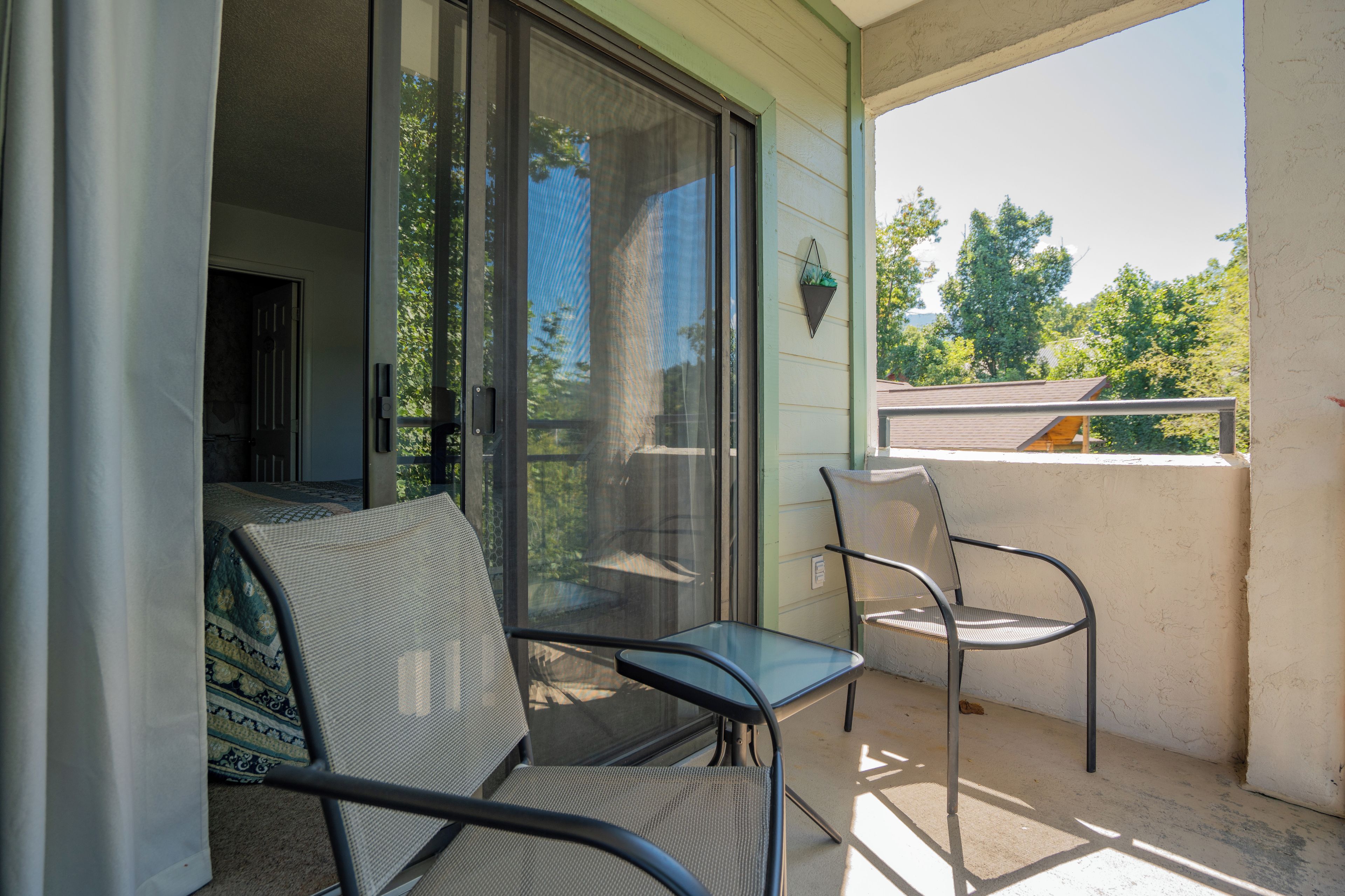 Ein Balkon mit Glastür, einem Stuhl und einem kleinen Tisch.