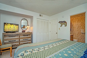 A bedroom with a bed, dresser, mirror, and a wall-mounted clock. - Laurel Inn 411 is a beautiful condo with private balcony close to downtown (Gatlinburg)