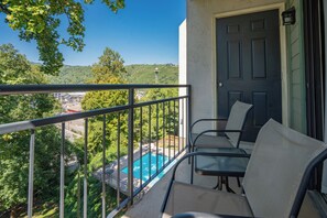 A balcony with a view of a swimming pool, a door, and a chair.
