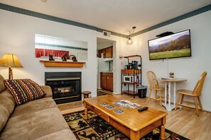 A living room with a sofa, coffee table, fireplace, and a TV mounted on the wall.