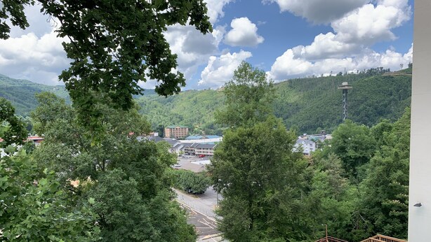 A pool area with lounge chairs and a view of a parking lot and buildings in the background. - Laurel Inn 411 is a beautiful condo with private balcony close to downtown (Gatlinburg)
