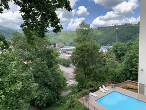 A pool area with lounge chairs and a view of a parking lot and buildings in the background. - Laurel Inn 411 is a beautiful condo with private balcony close to downtown (Gatlinburg)
