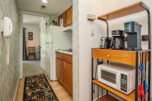 A compact kitchen with a microwave, coffee maker, and toaster on a shelf, a refrigerator, and a chair in the background. - Laurel Inn 411 is a beautiful condo with private balcony close to downtown (Gatlinburg)
