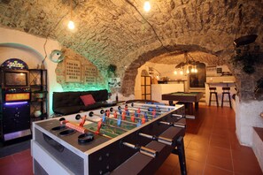 Una habitación con mesa de futbolín, mesa de billar y jukebox.