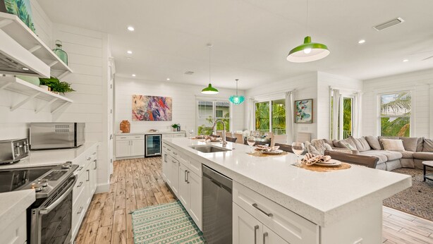 A modern kitchen with white cabinetry, a central island, and a dining area with a sofa and coffee table.
