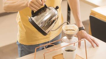 A person pouring coffee from a kettle into a coffee maker.