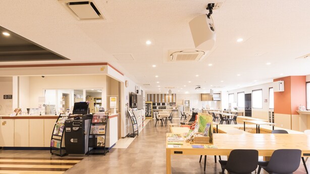 A spacious indoor area with a reception desk, seating arrangements, and a counter with a coffee machine.