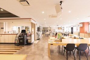 A spacious indoor area with a reception desk, seating arrangements, and a counter with a coffee machine.