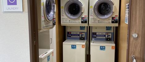 A laundry room with three stacked dryers and two washing machines, each labeled with numbers.