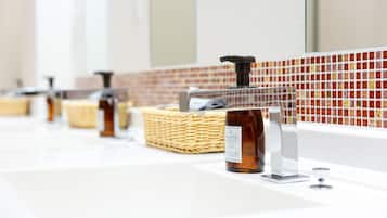 A bathroom with multiple sinks, each equipped with a soap dispenser and a glass. There is a wicker basket placed on one of the sinks.
