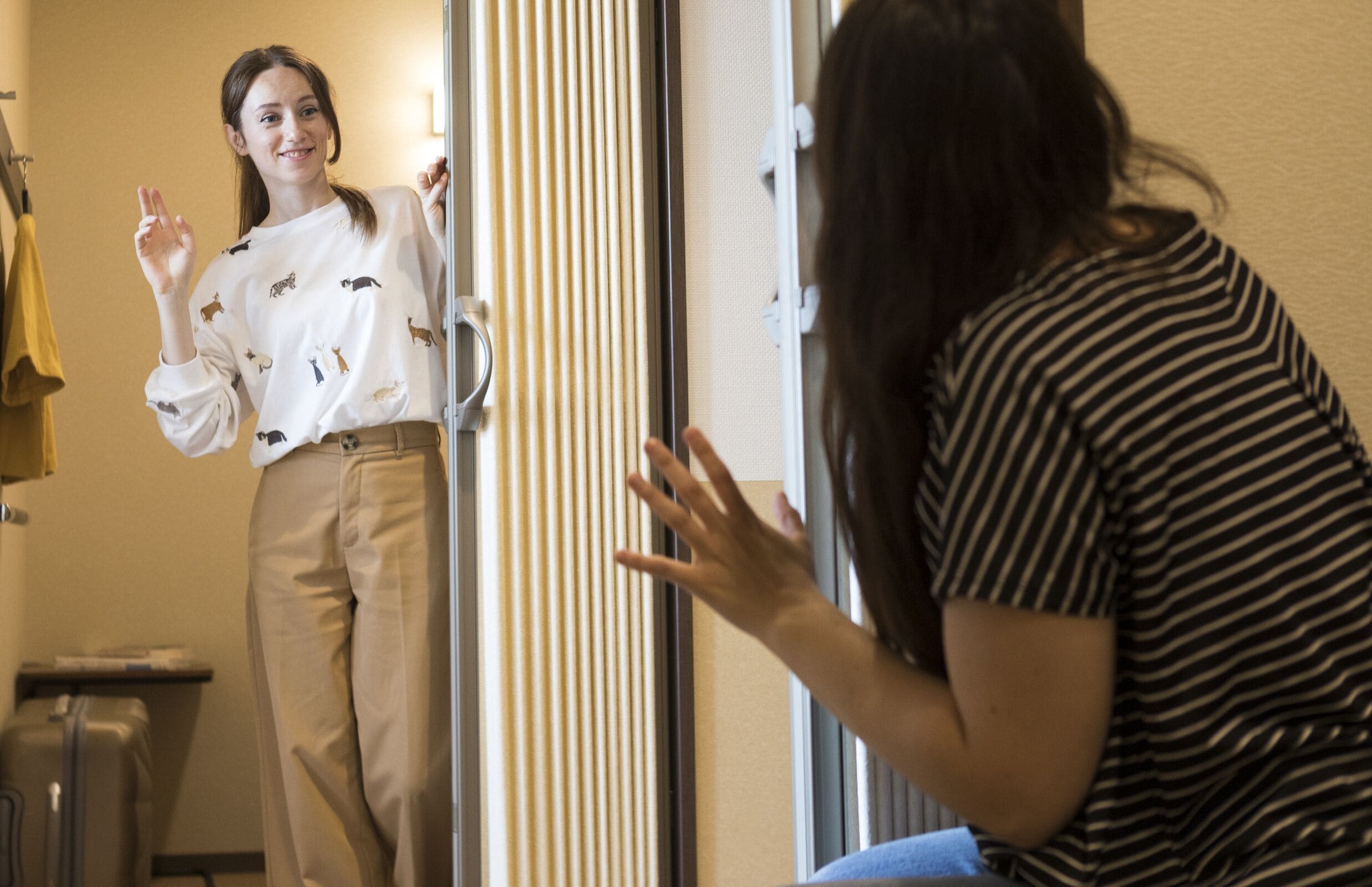 A hotel room with a sliding door, a suitcase, and a coat rack.