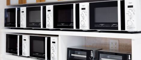 A kitchen with multiple microwave ovens and a toaster oven on display.