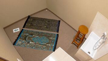 Un baño con un lavabo, un taburete de madera y dos alfombras estampadas.