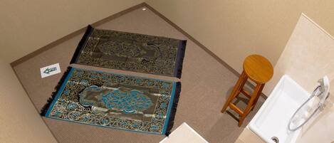 Une salle de bain avec un lavabo, un tabouret en bois et deux tapis à motifs.