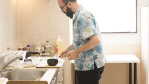 A person cooking in a modern kitchen with a sink, stove, and various kitchen items.