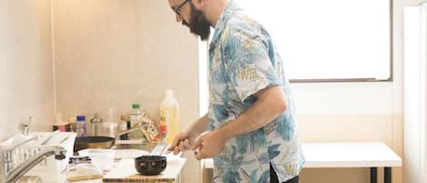 A person cooking in a modern kitchen with a sink, stove, and various kitchen items.