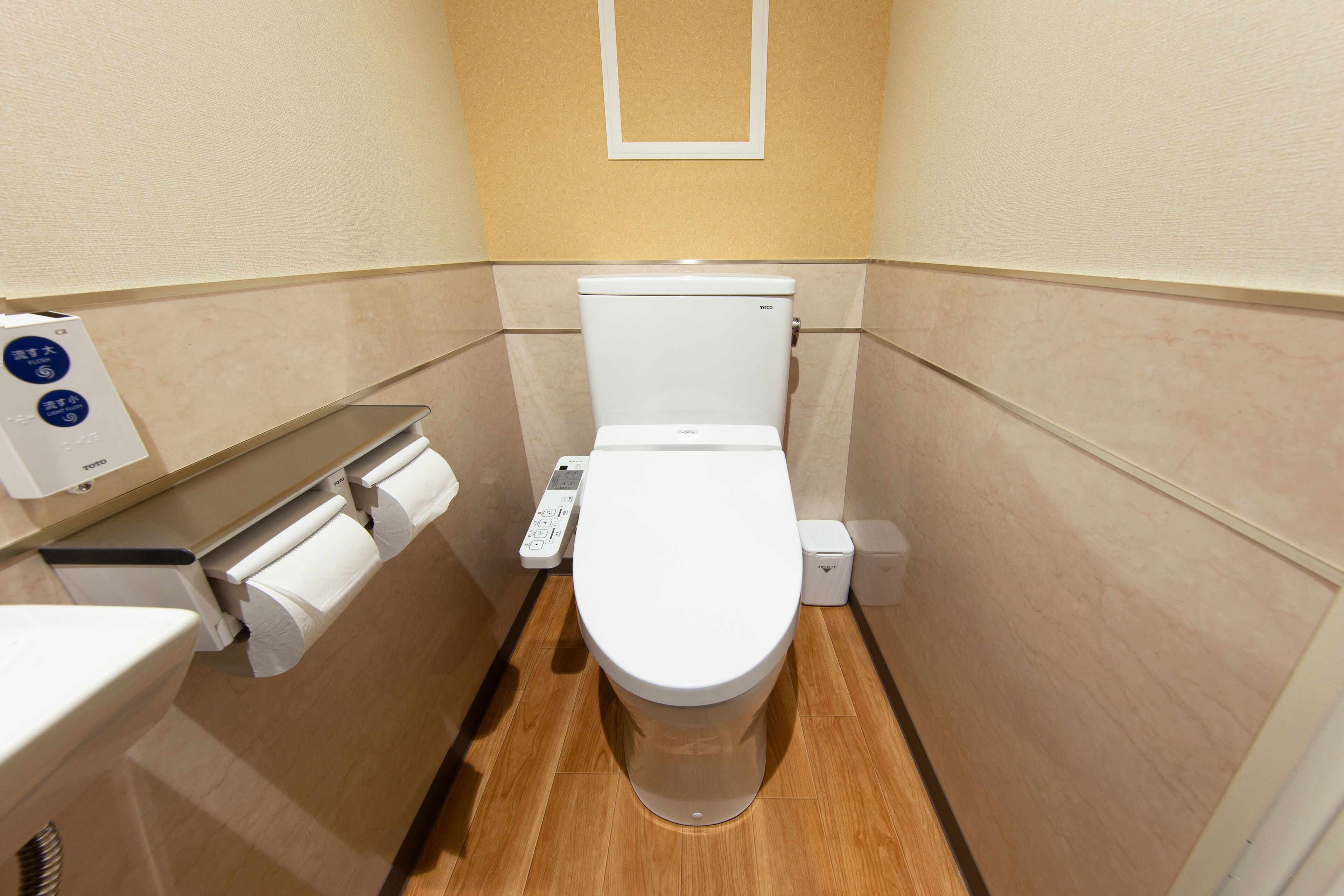 A small, modern bathroom with a toilet, a toilet paper holder, and a hand dryer.
